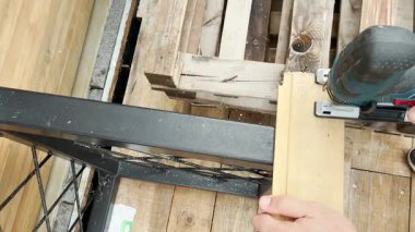 Tamirci adam, tahta bloğu testereyle keser.