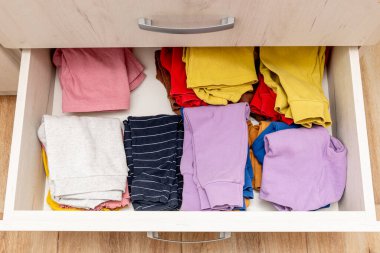 Gardırop çekmecesini aç, çocuk kıyafetlerinin arasında depolama yap.