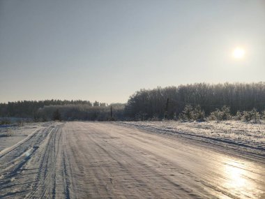 Mavi kış gökyüzünün altında izleri olan karla kaplı bir tarla. Açık arazili kırsal kış manzarası.