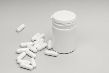 Beyaz bir konteynır gri bir yüzeye yerleştirilir ve bazı kapsüller etrafa saçılmıştır. Görünürde başka bir nesne olmadan ayarlar basittir. Işık konteynır ve kapsüllere düşer.