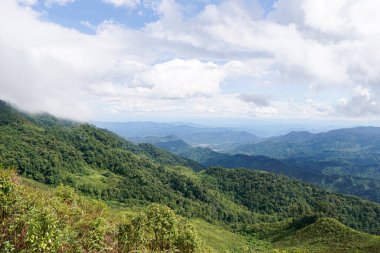 Bereketli yeşil dağ sıralarının nefes kesici panoramik manzarası bulutlu bir gökyüzü altında sisli, manzaralı tropik dağlık arazi.