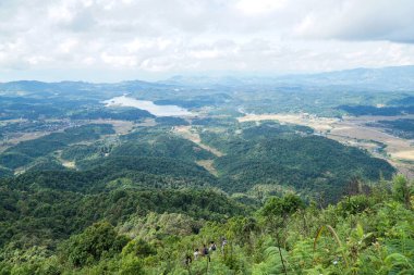 Aşağıdaki vadide küçük bir köyü olan yemyeşil dağların panoramik manzarası ve dingin bir göl.