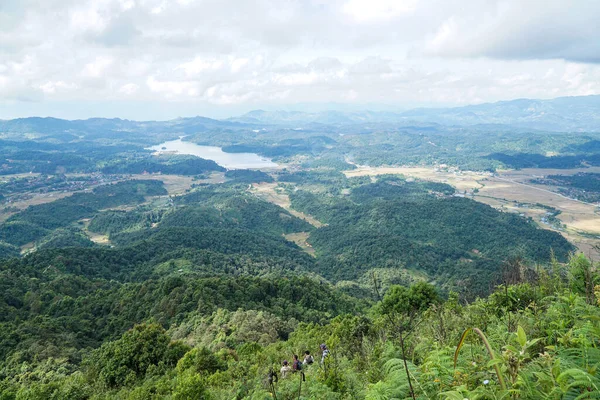 Aşağıdaki vadide küçük bir köyü olan yemyeşil dağların panoramik manzarası ve dingin bir göl.