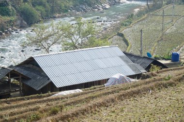 Kırsal Vietnam köyü kıvrımlı demir çatıları, teraslı tarlaları ve akan bir nehri var..