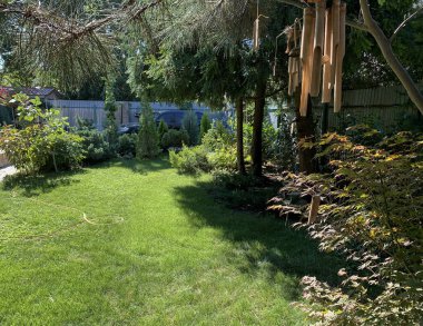 Bahçe rüzgârının çanları yeşil çimlerin üzerinde sallanıyor huzurlu bir yaz bahçesinde.