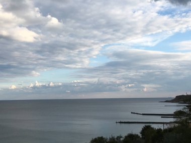 Sakin Karadeniz, sakin ufuk ve bulutlu gökyüzü altında beton rıhtımlar, sakin kıyı sahili.