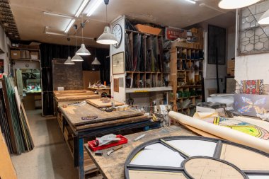 El yapımı camlar, aletler ve çalışma tezgahlarıyla geleneksel bir vitray atölyesi. Sanatsal cam işçiliğinin özgün atmosferi. Renkli cam parçaları ve boyalı cam..