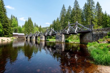 Modrava, Sumava Ulusal Parkı 'ndaki tarihi ahşap kapı köprüsü. Vydra Nehri üzerindeki geleneksel kereste yapısı orman manzarası, seyahat ve turizm temaları için ideal..