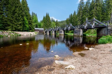 Modrava, Sumava Ulusal Parkı 'ndaki tarihi ahşap kapı köprüsü. Vydra Nehri üzerindeki geleneksel kereste yapısı orman manzarası, seyahat ve turizm temaları için ideal..