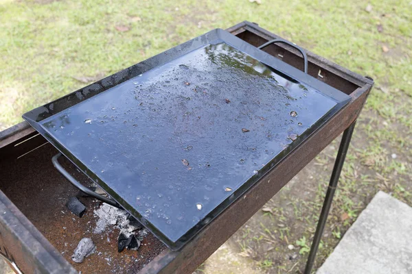 Paslı bir ızgarada kirli ve kullanılmış siyah ızgara tabağı.