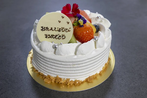 Renkli taze meyvelerle süslenmiş lüks beyaz doğum günü pastası.