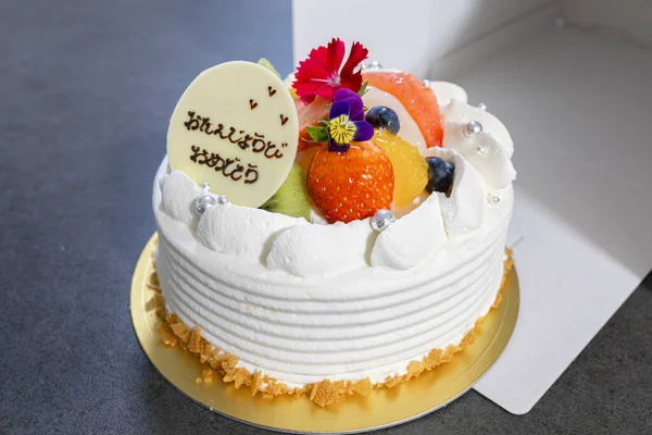Meyveli, kremalı ve Japonca tebrik mesajlı doğum günü pastası.