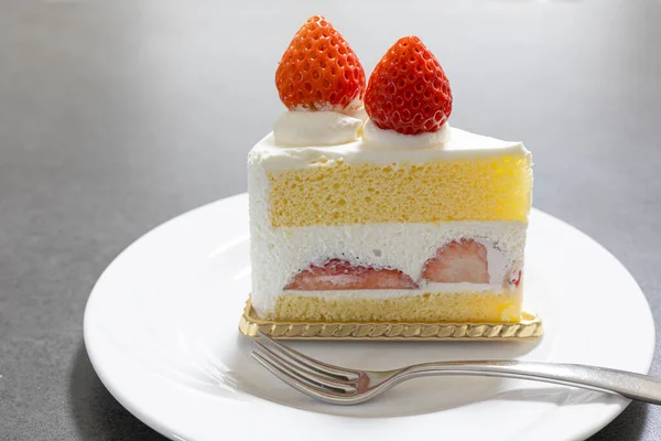 Çatallı beyaz bir tabakta tatlı çilekli pasta dilimi