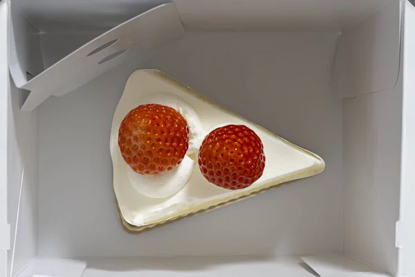 Beyaz paket servis kutusundaki çilekli pasta diliminin genel görünümü