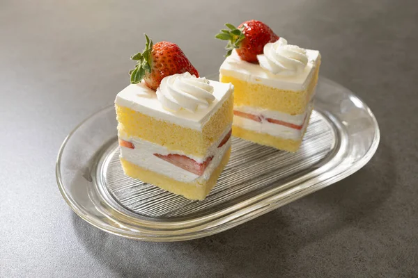 Bardaktaki servis tepsisinde iki dilim çilekli kek