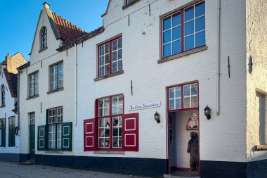 Bruges, Belçika, 26 Aralık 2025. Penceresinde renkli panjurları ve oyuncak ayıları olan büyüleyici bir dükkan. Sıcak butik dış görünüş, sıcak ışık ve neşeli ayı heykeli sokaklara tatlı bir peri masalı hissi katar..