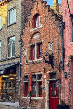 Bruges, Belçika, 26 Aralık 2025. Bruges 'ün göbeğinde bulunan tarihi tuğla ev cephesi belirgin basamaklar ve oyulmuş taş elementlerle dolu. Sıcak dar sokak atmosferi eski Avrupa mimarisinin ve zamansız mirasının ruhunu yansıtıyor