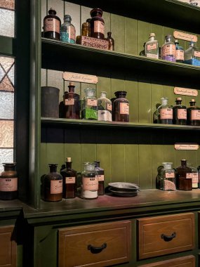 Lahey, Hollanda 5 Kasım 2024 tarihi bir stüdyo veya eczacı sahnesi olarak düzenlenmiş antika şişe ve konteynırlar ile yeşil ahşap dolap Madurodam park müzesi sergisi içinde.