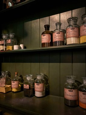 Lahey, Hollanda 5 Kasım 2024: Madurodam 'daki tarihi bir serginin içindeki ahşap raflarda sergilenen ve sanatçılar ve eczacılar tarafından kullanılan geleneksel materyalleri gösteren antika cam kavanozlar.