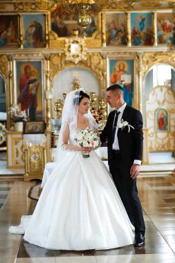 Gelin ve damat kilisede yakın dururlar. Gelin beyaz bir elbise giyerken damat takım elbise giyer. Düğün törenlerinde ellerinde çiçeklerle birbirlerine bakarlar..