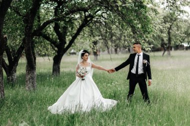 Bir çift düğün törenlerinde çimenli bir alanda birlikte dururlar. El ele tutuşup birbirlerine gülümserler. Ağaçlar etraflarını sarar ve güneş doğar.