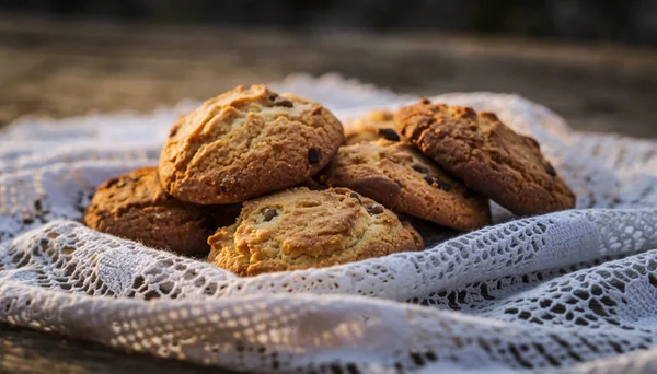Yakın plan çekimde taze çikolatalı çörekler ince beyaz dantelli kumaş üzerine istiflenmiş, bulanık ahşap bir arka plan..