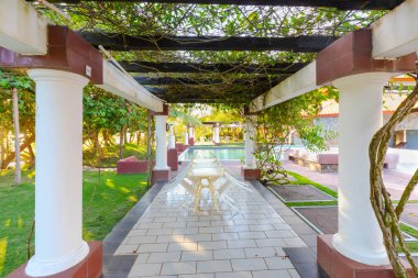 Panama Barqueta plajı, tropik bitki örtüsünde yüzme havuzu olan bir pergola altındaki açık hava restoranının masaları.