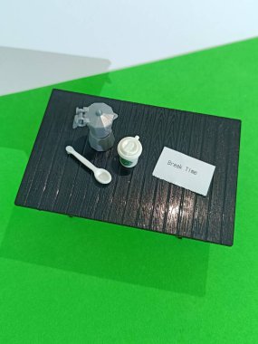 Minyatür bir moka kabı, fincan ve kaşık koyu renkli bir yüzey üzerinde 