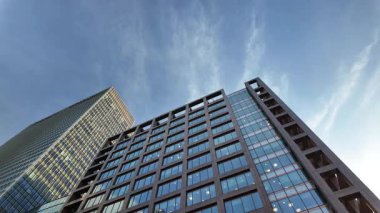 Gökdelenlerin üstünde gökyüzü değişiyor. Düşük bir açıyla, bulutlar tepemize üşüşür. Bu zaman diliminde modern binalar gün ilerledikçe hareketsiz kalır..