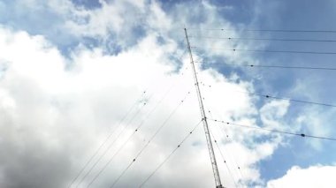 Kabarık bulutlar uzun bir radyo kulesinin yanından geçiyor.