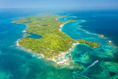Kolombiya, Cartagena 'daki Rosario Adaları' nın ana adasının havadan panoramik görüntüsü. Deniz, turkuaz ve kristal berrak suları koyu mercan yamalarıyla sergiliyor. Ada birkaç görünür çatısı olan yemyeşil bitki örtüsüyle kaplı..