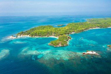 Kolombiya, Cartagena 'da, turkuaz Karayip suları, görünür mercan resifleri, tropikal ağaçlar ve adaya yakın demirlemiş çok sayıda tekneyle çevrili İHA görüntüsü yakalamış..