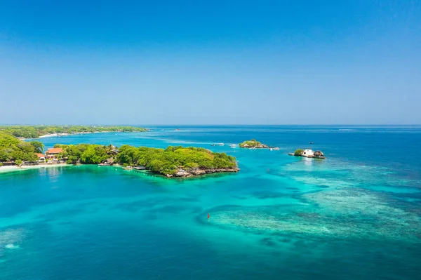 Cartagena, Kolombiya yakınlarındaki Islas del Rosario 'nun hava görüntüsü. Ada yoğun yeşil bitki örtüsüyle kaplıdır ve güneşli bir günde görünen mercan resifleri ve tekneleriyle turkuaz sularla çevrilidir..