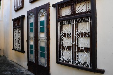 Malezya 'nın Penang kentindeki Jawi Peranakan Malikanesi' nde canlı ahşap kepenkleri ve süslü beyaz duvarları olan geleneksel bir miras penceresinin ayrıntılı görüntüsü.