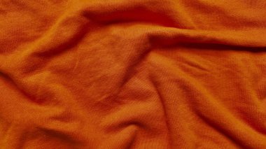 Yumuşak dalgalarda dalgalanan canlı terracotta turuncu forma kumaşı sonbahar duvar kağıdı veya reklam afişi için sıcaklığı çağrıştıran yakın doku.