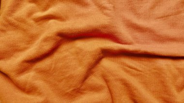 Yumuşak kıvrımlı turuncu pamuk kumaş dokusu ve yakın plan kırışıklıkları tasarım için sıcak sonbahar örtüsünü çağrıştırıyor.