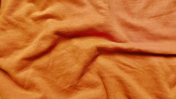 Yumuşak kıvrımlı turuncu pamuk kumaş dokusu ve yakın plan kırışıklıkları tasarım için sıcak sonbahar örtüsünü çağrıştırıyor.