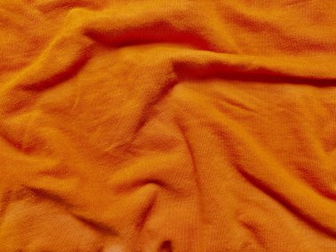 canlı turuncu kumaş dokusu yumuşak kıvrımlar ve ılık parıltı ile yakın çekim sıcak sonbahar atmosferini çağrıştırıyor