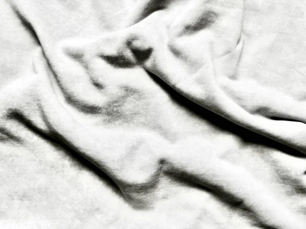 Kırışık beyaz kumaş kıvrımlarının tek renkli görüntüsü soyut dokuya yumuşak gölgeler bırakarak sükunet minimalizmi ve dokunsal derinliği çağrıştırıyor.