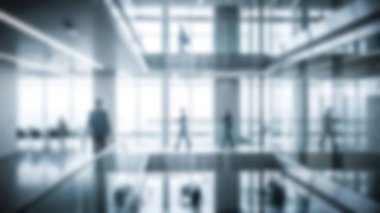 Doğal ışık alan, uzayda hareket eden insanların bulanık figürlerini aydınlatan, iş etkinliği ve kurumsal atmosfer hissi uyandıran, modern ofis içlerinin yumuşak odak görüntüsü..