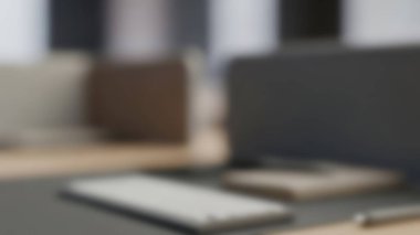 Bir masadaki dizüstü bilgisayar, akıllı telefon ve not defterinin yer aldığı bulanık bir çalışma alanı görüntüsü.