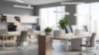 Birden fazla masa, bilgisayar ve bitkinin yer aldığı modern ve parlak bir ofis..