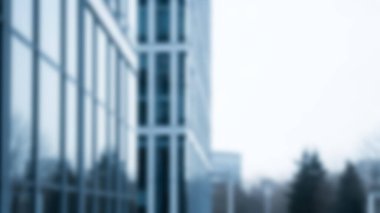 Çağdaş bir ofis binası, parlak cam bir cephe ile, serin mavi bir tonu yansıtıyor..