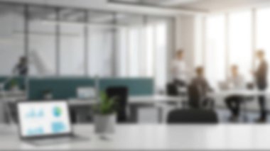 Önplanda veri tablosunu gösteren bir dizüstü bilgisayarla bulanık bir modern ofis..