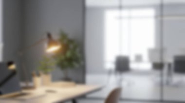 Modern bir ofis, içinde dizüstü bilgisayar, lamba ve yeşil bir bitki bulunan doğal ışıkla yıkanmış..