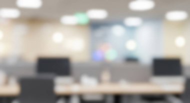 Blurred modern office interior with workstations and ceiling lights.