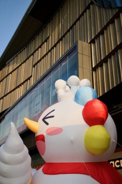 Kocaman, şişme bir maskot alışveriş merkezinin önünde dondurma tutuyor.