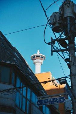 Busan Kulesi manzarası gölgede eski binalar ve bulutsuz açık mavi gökyüzü.