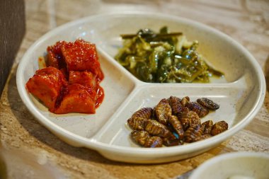 Kızarmış İpek Böceği Pupae, Baharatlı Turp ve Yosun Salatası ile nefis Kore yemeklerini yakından izleyin.