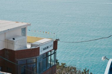 Deniz kenarındaki kafe binasında deniz kenarında tabela var..